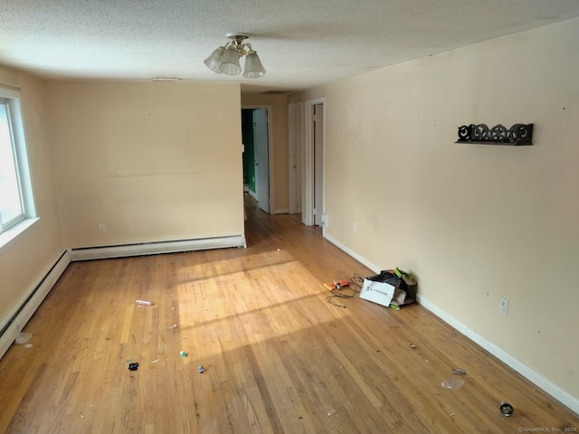 spare room featuring a baseboard radiator, wood-type flooring, and a textured ceiling