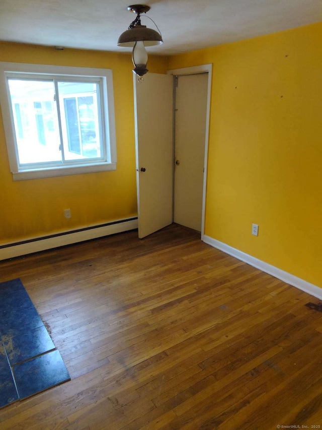 unfurnished room featuring baseboard heating and dark hardwood / wood-style floors