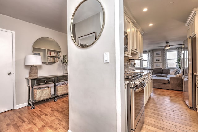 kitchen featuring light hardwood / wood-style floors, cream cabinetry, ceiling fan, and appliances with stainless steel finishes