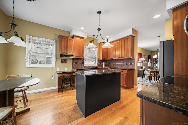 kitchen with a center island, pendant lighting, light hardwood / wood-style floors, and decorative backsplash