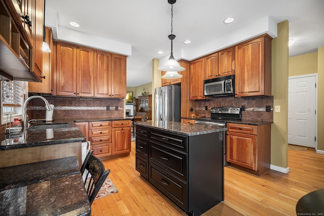 kitchen with pendant lighting, sink, dark stone countertops, a center island, and stainless steel appliances