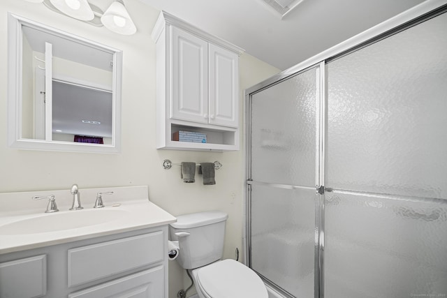 bathroom with vanity, a shower with shower door, and toilet