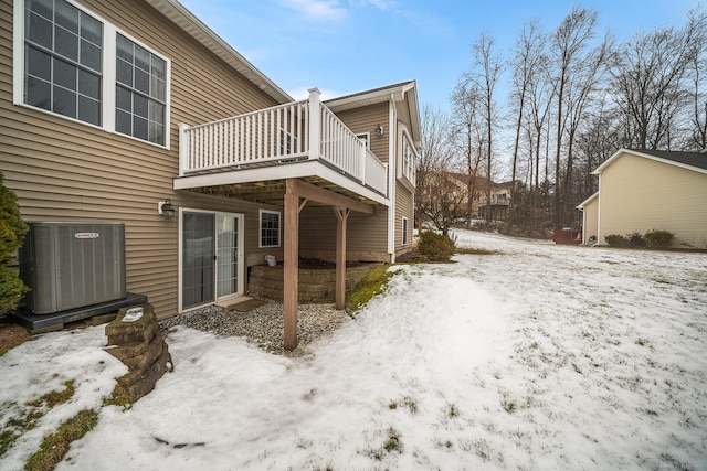 snow covered property with cooling unit and a wooden deck