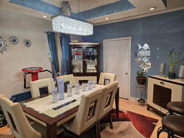 dining space featuring a notable chandelier, a tray ceiling, and light hardwood / wood-style floors