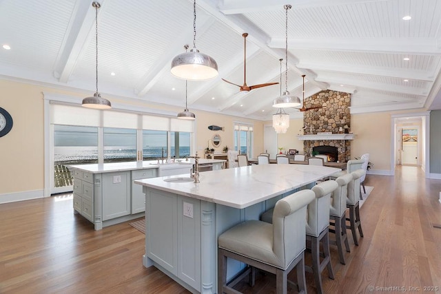464 Park Blvd, Stratford, CT 06615 - kitchen with a center island with sink, lofted ceiling with beams, a kitchen breakfast bar, wood finished floors, and a stone fireplace