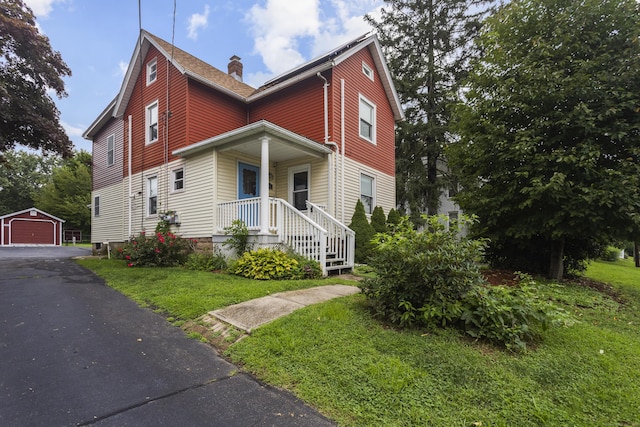 view of front of house featuring an outbuilding, a garage, and a front lawn