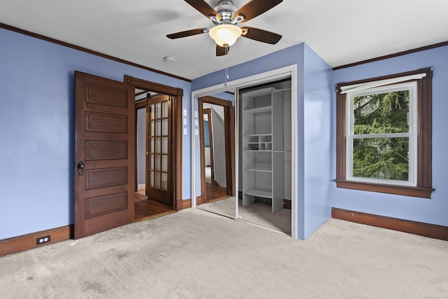 unfurnished bedroom with a closet, ornamental molding, carpet, ceiling fan, and french doors