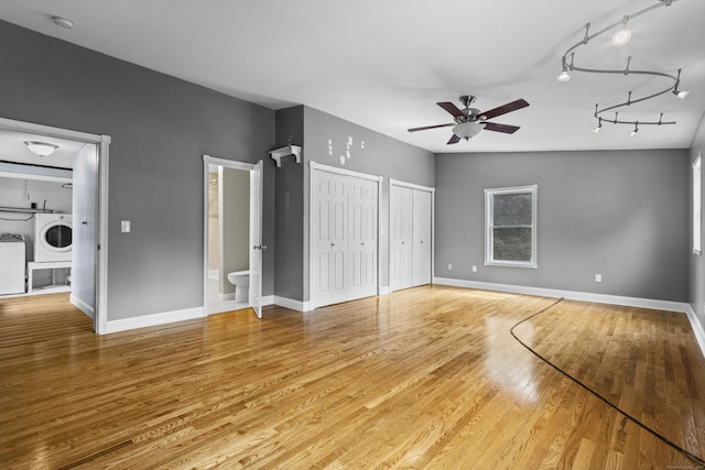 unfurnished bedroom featuring washer / clothes dryer, two closets, ensuite bathroom, and hardwood / wood-style flooring