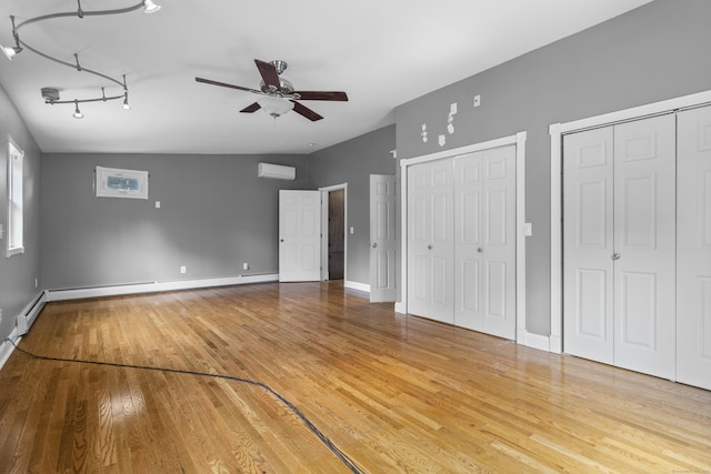 unfurnished bedroom featuring multiple closets, hardwood / wood-style floors, a wall mounted AC, and a baseboard heating unit