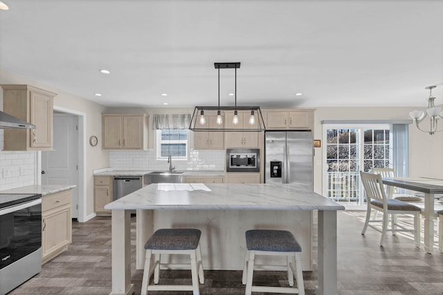 kitchen with hanging light fixtures, appliances with stainless steel finishes, a center island, and sink