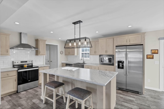 kitchen featuring appliances with stainless steel finishes, sink, hanging light fixtures, a center island, and wall chimney exhaust hood