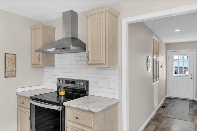 kitchen with dark wood-type flooring, wall chimney range hood, electric range, and light brown cabinetry