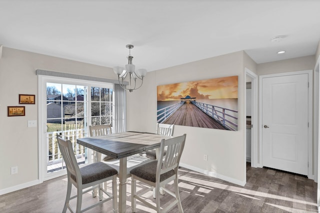 dining area with dark wood-type flooring and a notable chandelier