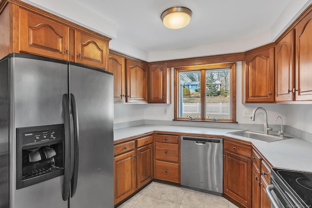 kitchen with appliances with stainless steel finishes, sink, and light tile patterned floors