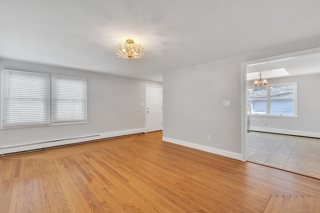 empty room with an inviting chandelier, light hardwood / wood-style floors, and a baseboard heating unit