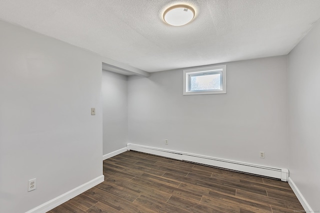 basement featuring dark hardwood / wood-style flooring, a baseboard heating unit, and a textured ceiling