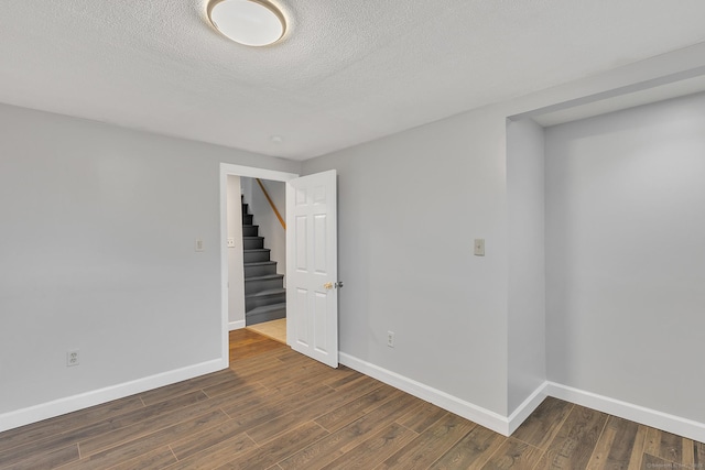 unfurnished room featuring a textured ceiling and dark hardwood / wood-style flooring