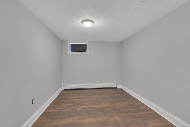 spare room featuring a baseboard heating unit, dark hardwood / wood-style floors, and a textured ceiling