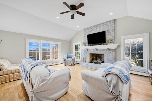 living room featuring lofted ceiling, light wood-type flooring, baseboard heating, ceiling fan, and a fireplace