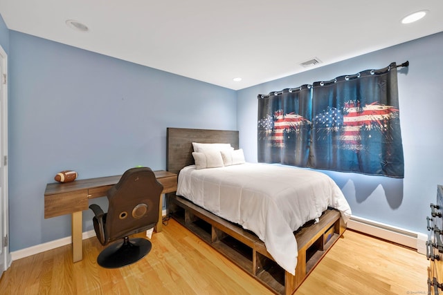 bedroom with hardwood / wood-style floors and a baseboard radiator