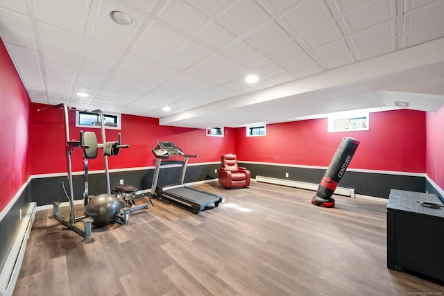 workout area featuring wood-type flooring and a baseboard heating unit