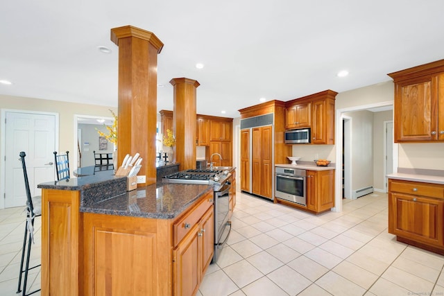 kitchen featuring sink, ornate columns, appliances with stainless steel finishes, kitchen peninsula, and a baseboard heating unit