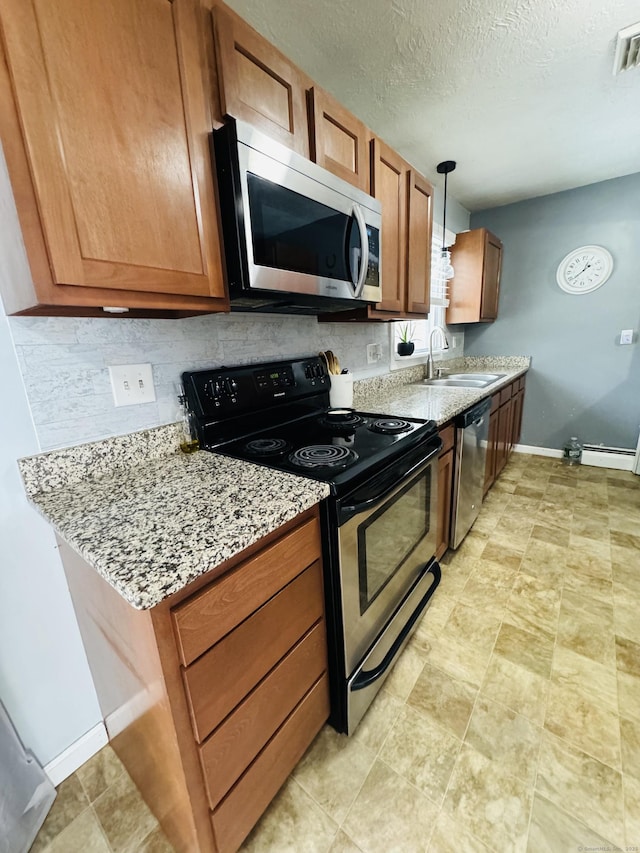 kitchen with sink, stainless steel appliances, light stone countertops, decorative backsplash, and decorative light fixtures