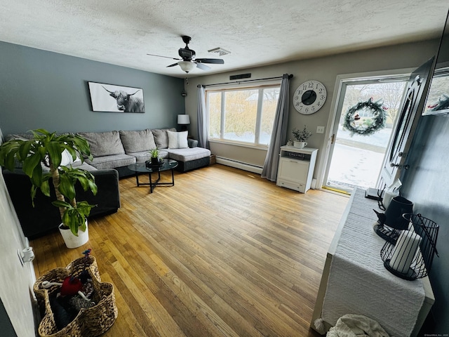 living room with hardwood / wood-style flooring, ceiling fan, a textured ceiling, and baseboard heating