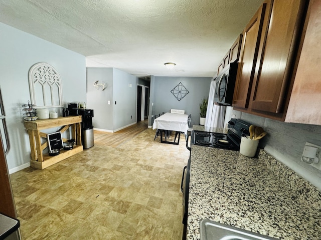 kitchen featuring black range with electric stovetop, light stone countertops, and a textured ceiling