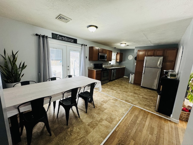 dining space with sink, a textured ceiling, and french doors