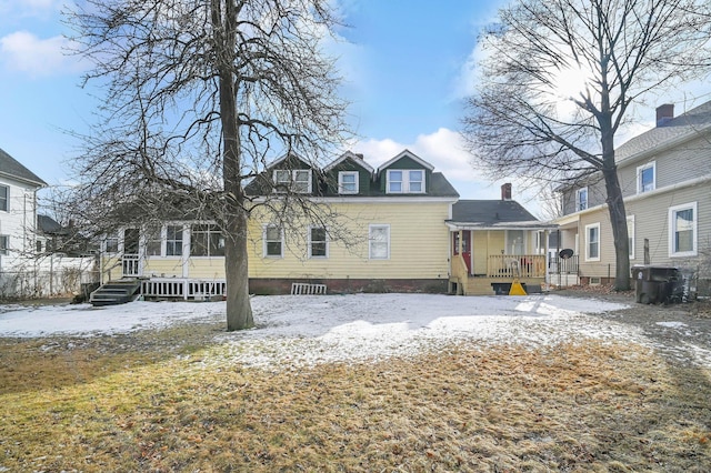 snow covered rear of property with a wooden deck