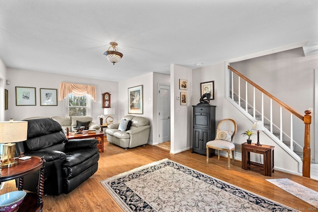 living area featuring baseboards, stairway, and wood finished floors