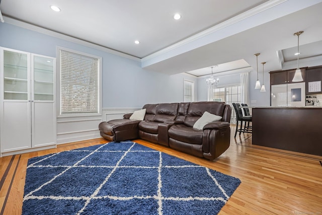 living room with crown molding, wood-type flooring, and a chandelier