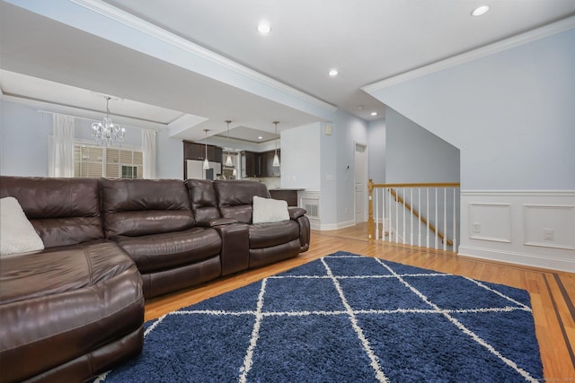 living room with hardwood / wood-style flooring, ornamental molding, a raised ceiling, and an inviting chandelier