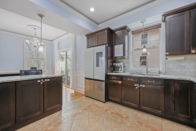 kitchen with pendant lighting, sink, backsplash, stainless steel fridge, and dark brown cabinetry