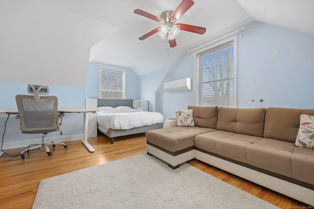 bedroom with ceiling fan, lofted ceiling, a wall mounted AC, and light wood-type flooring