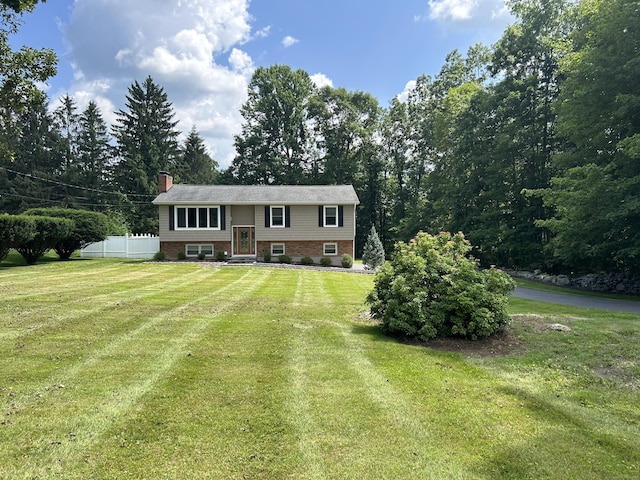 split foyer home with a front yard, fence, and a chimney