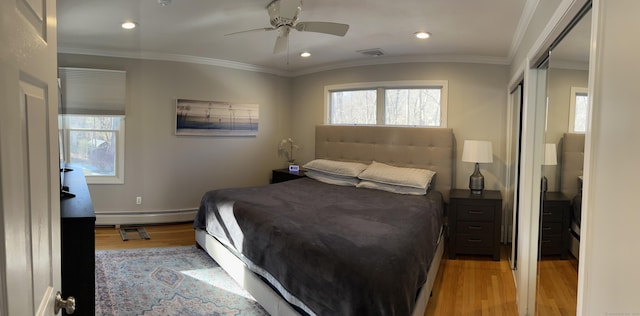 bedroom featuring a baseboard heating unit, light wood-type flooring, multiple windows, and crown molding