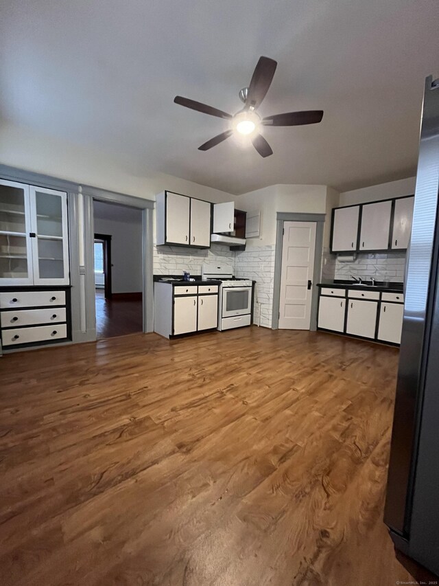 kitchen featuring tasteful backsplash, hardwood / wood-style flooring, stainless steel fridge, and white gas range oven