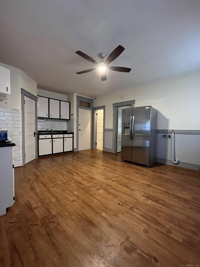 kitchen with white cabinets, stainless steel fridge, light wood-type flooring, and decorative backsplash