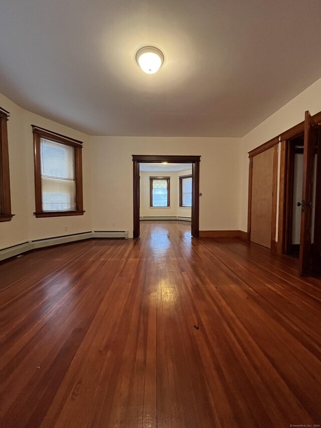 empty room with a baseboard radiator and dark wood-type flooring