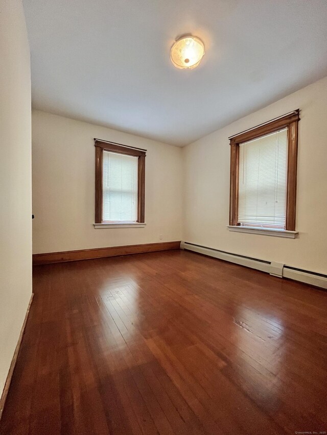 unfurnished room with a baseboard heating unit and dark wood-type flooring