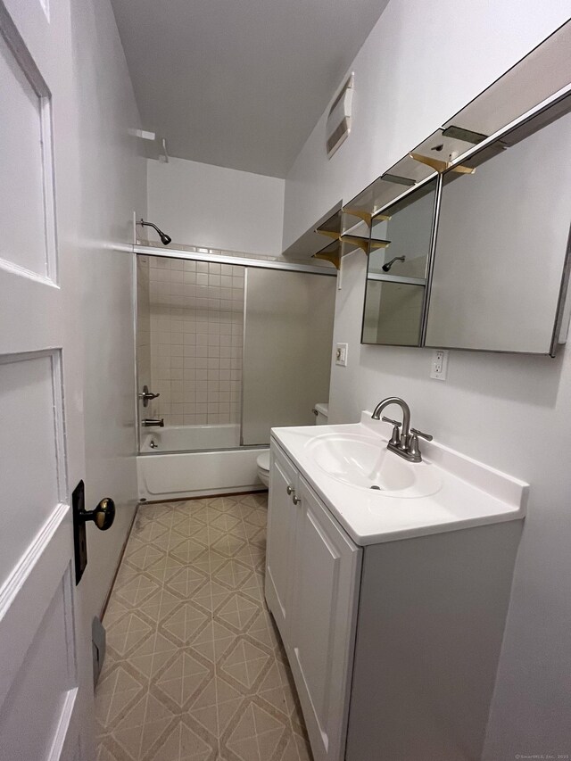 full bathroom featuring vanity, shower / bath combination with glass door, and toilet