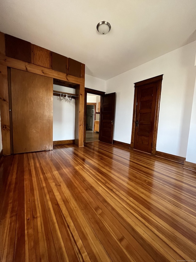 unfurnished bedroom with dark hardwood / wood-style floors and a closet