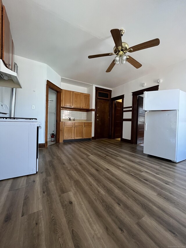 kitchen with dark wood-type flooring, white appliances, ceiling fan, and backsplash