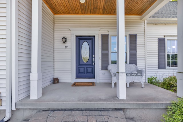 entrance to property featuring a shingled roof and covered porch