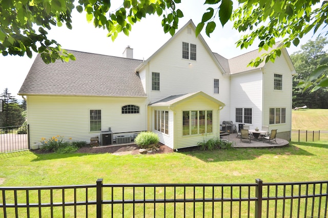 back of property with a yard, fence private yard, a patio, and a chimney