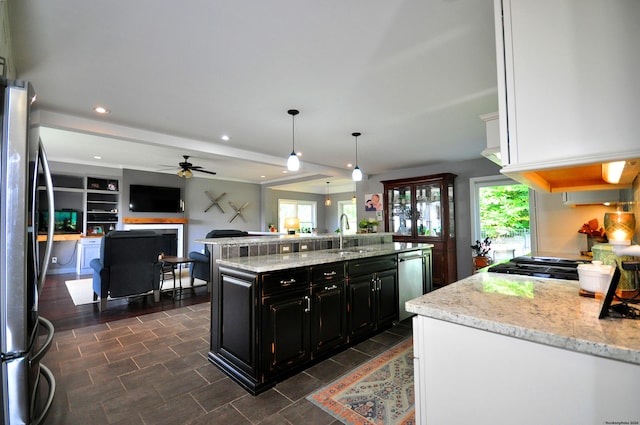 kitchen featuring a kitchen island with sink, stainless steel appliances, a sink, open floor plan, and dark cabinetry