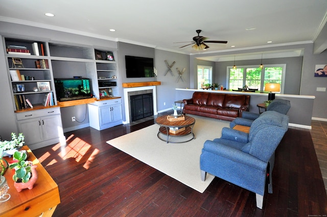 living area featuring baseboards, a fireplace with flush hearth, ornamental molding, dark wood-type flooring, and recessed lighting