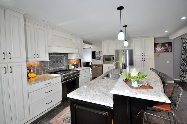 kitchen featuring stainless steel appliances, a sink, a large island, decorative backsplash, and custom range hood